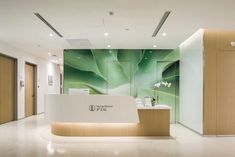 an office lobby with a large green plant on the wall and a white reception counter