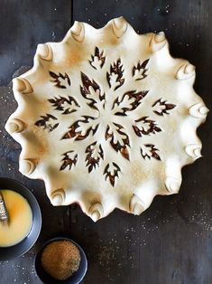 a pie pan and bowl filled with orange liquid on top of a wooden table next to a spoon