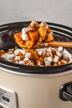 a spoon full of marshmallows in an electric crock pot