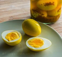 an open hard boiled egg on a plate next to a jar of pickled eggs