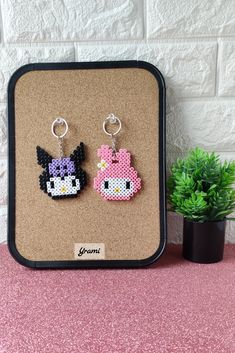 two earrings are sitting on a table next to a potted plant and brick wall