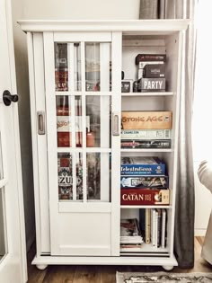 a white book case filled with books in a living room next to a door and window