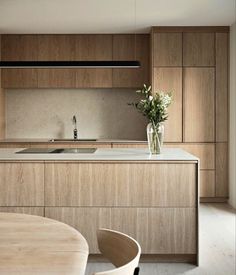 a modern kitchen with wooden cabinets and an island in the middle is seen from across the room