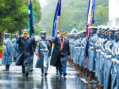 men in uniforms walking down the street with flags on their shoulders and medals around their necks