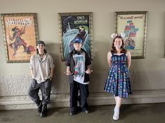 three people standing next to each other in front of posters