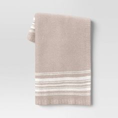 a beige towel with white stripes on the bottom and side, hanging from a gray wall