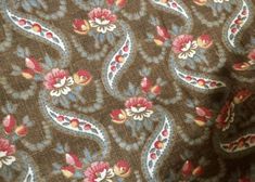 a close up view of a tie with red and blue flowers on brown fabric,