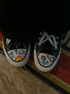 someone is wearing black and white shoes with colorful designs on the bottom, while they are standing in front of a rug