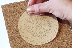 a person is making a paper doily on a cork board with scissors and glue