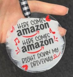 a hand holding a badge that says here comes amazon here comes amazon right down my driveway