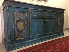 an old blue cabinet with ornate carvings on the doors and drawers is sitting in a room