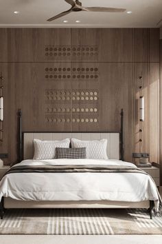 a large bed sitting under a ceiling fan next to a wooden paneled bedroom wall