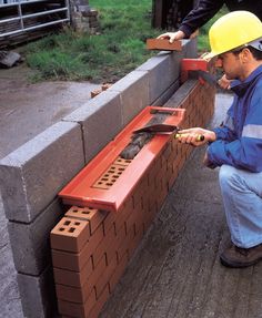 two men in hardhats are working on some bricks