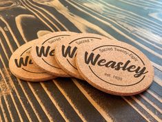 three cork coasters sitting on top of a wooden table with the words we w weasely printed on them