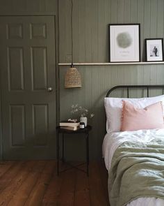 a bed sitting next to a green door and a lamp on top of a table