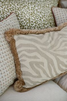 a close up of some pillows on a couch with zebra print and brown trimmings