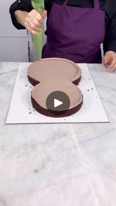 a person in an apron cutting a cake with a knife and flower on the table