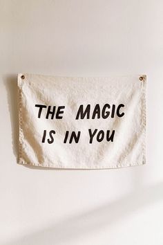 a towel hanging on the wall that says, the magic is in you with black letters