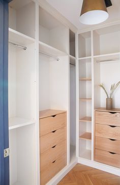 an empty closet with wooden drawers and white shelving unit in the corner between two walls