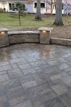 an outdoor patio with stone walls and lights on the side walk, in front of a house