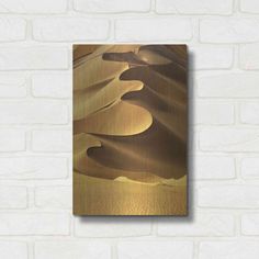 an abstract painting on a brick wall with gold foil in the shape of sand dunes