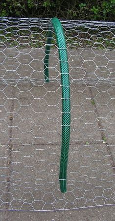 a close up of a wire fence with a green hose attached to it