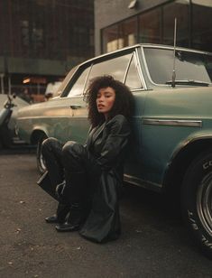 a woman sitting on the ground next to a car