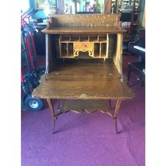 an old fashioned wooden desk with drawers on the top and bottom shelf, sitting in a purple carpeted room