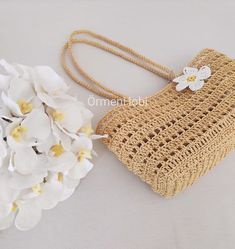 a crocheted purse next to white flowers