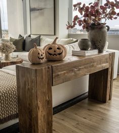 two carved pumpkins sitting on top of a wooden table in front of a window