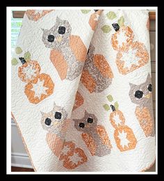 an orange and white cat quilt hanging on a window sill in front of a window