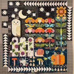 a quilted wall hanging with an owl and pumpkins on it's side