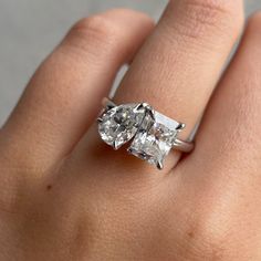 a woman's hand holding an engagement ring with two stones