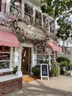 a store front with pink flowers on the windows and awnings over it's entrance