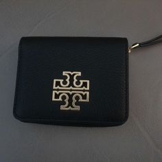 Welcome To Mishmoshsale.Com........Up For Sale Is An Authentic Black Tory Burch Britten Bi-Fold Wallet As Seen In The Pictures. This Stylish Black Wallet Measures Approximately 4.5 Inches Long And 3.5 Inches Wide And Offers 6 Credit Card Slots In Addition To One Coin Compartment With Zipper Enclosure And Paper Money Holder. It Also Offers The Snap On Front As Seen In The Pictures. Last One In Stock. Designer Black Compact Coin Purse, Designer Black Wallet With Gold-tone Hardware, Designer Black Wallets With Gold-tone Hardware, Black Wallets With Gold-tone Hardware For Daily Use, Tory Burch Britten, Tory Burch Wallet, Tory Burch Kira, Money Holder, Tory Burch Robinson