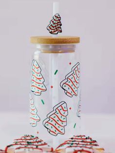 a glass cup filled with cookies and decorated christmas trees on top of each other, surrounded by small cookies