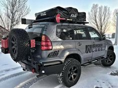 an suv parked in the snow with luggage strapped to it's roof rack and cargo bag on top