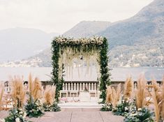 an outdoor ceremony setup with flowers and greenery in front of the water's edge