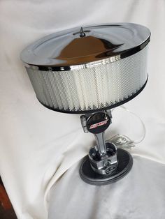 a black and silver lamp sitting on top of a white sheet