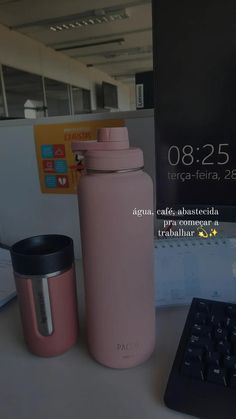 a pink water bottle sitting next to a keyboard and mouse on a desk in an office