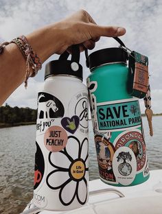 a person holding onto a water bottle on the back of a boat with stickers all over it