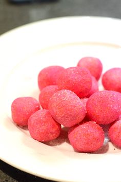 pink candy balls sitting on top of a white plate