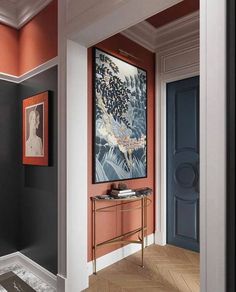 an entryway with orange and black walls, white trim and artwork on the wall