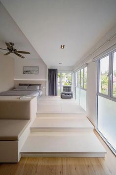 an empty bedroom with white walls and flooring, stairs leading up to the bed