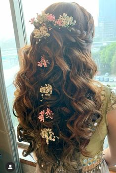 the back of a woman's head with flowers in her hair, looking out a window