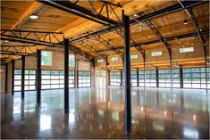 an empty building with lots of windows and metal beams on the ceiling is lit by lights