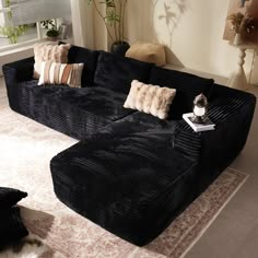 a large black couch sitting on top of a rug in a living room next to a window