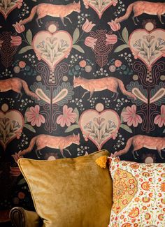 a brown couch sitting next to a black wallpaper covered in pink and orange flowers