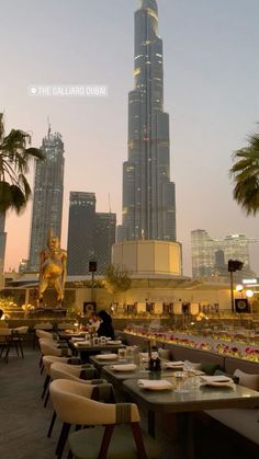 an outdoor dining area with tables and chairs in front of the burj building