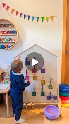 a little boy standing in front of a toy house